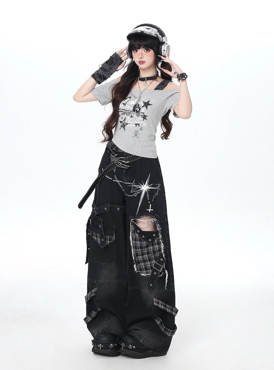 Person wearing a gray t-shirt with star designs and black ripped jeans on a white background