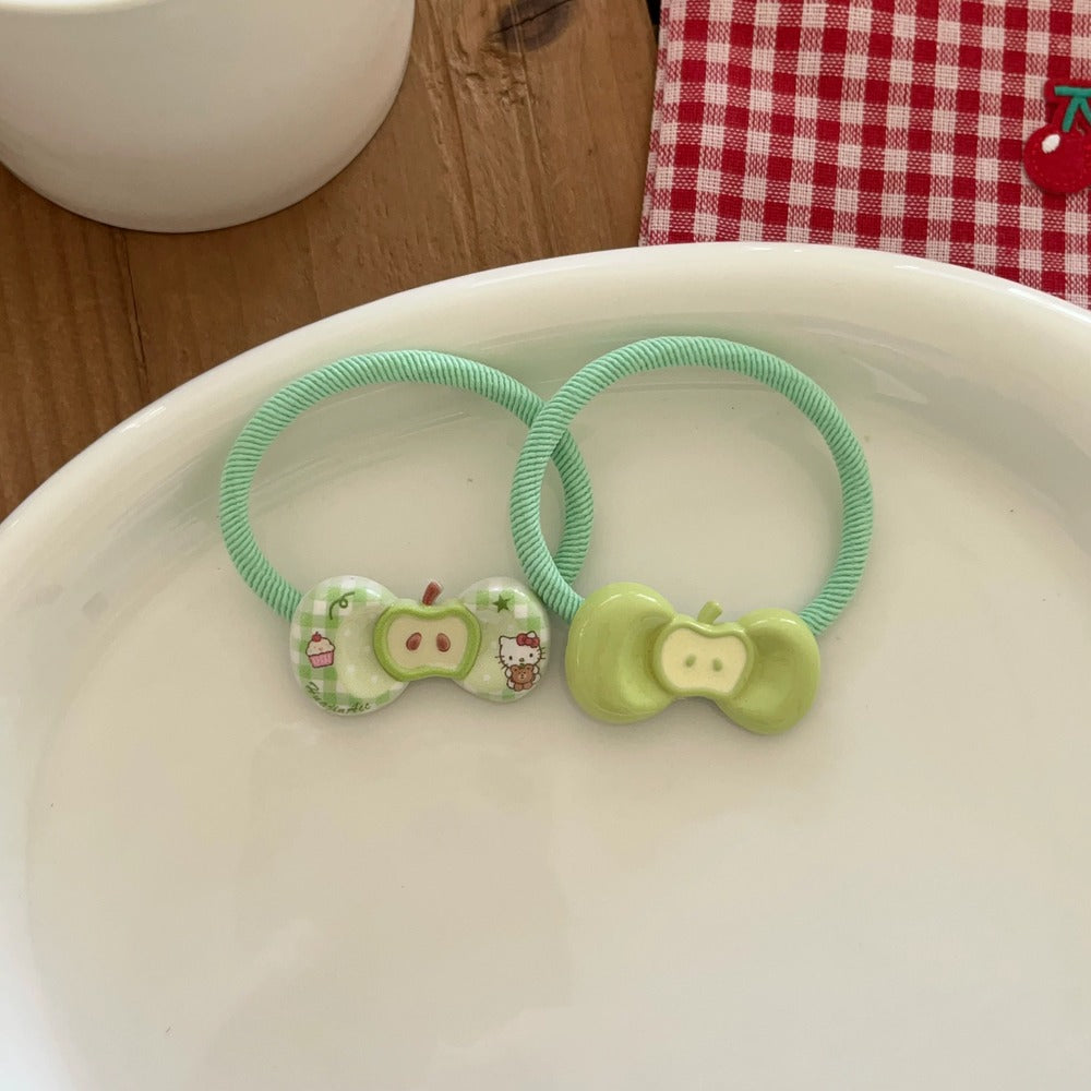 Two green hair ties with cartoon character designs on a white surface.