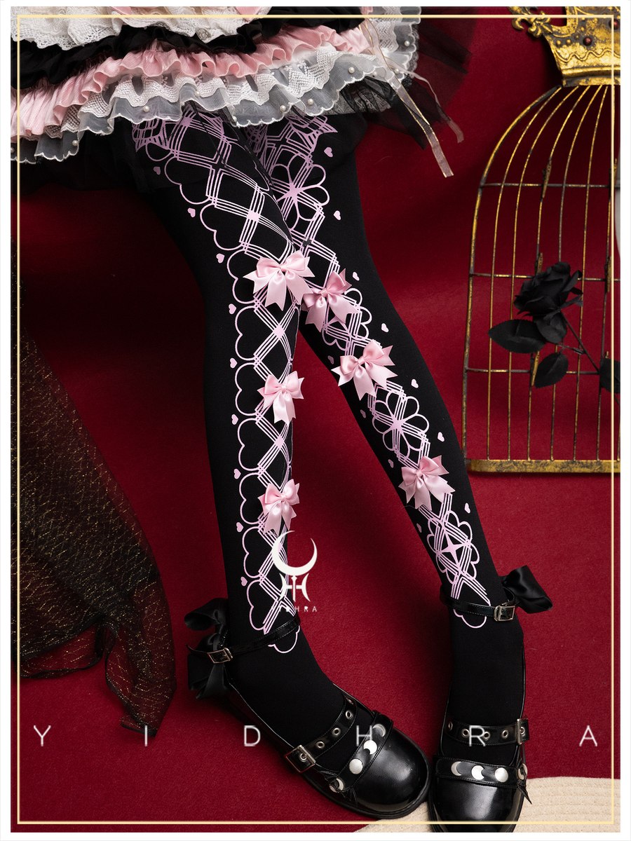 Black tights with white lattice patterns and pink bows, worn with black gothic shoes and a ruffled skirt, set against a dark red background with a gold birdcage prop.