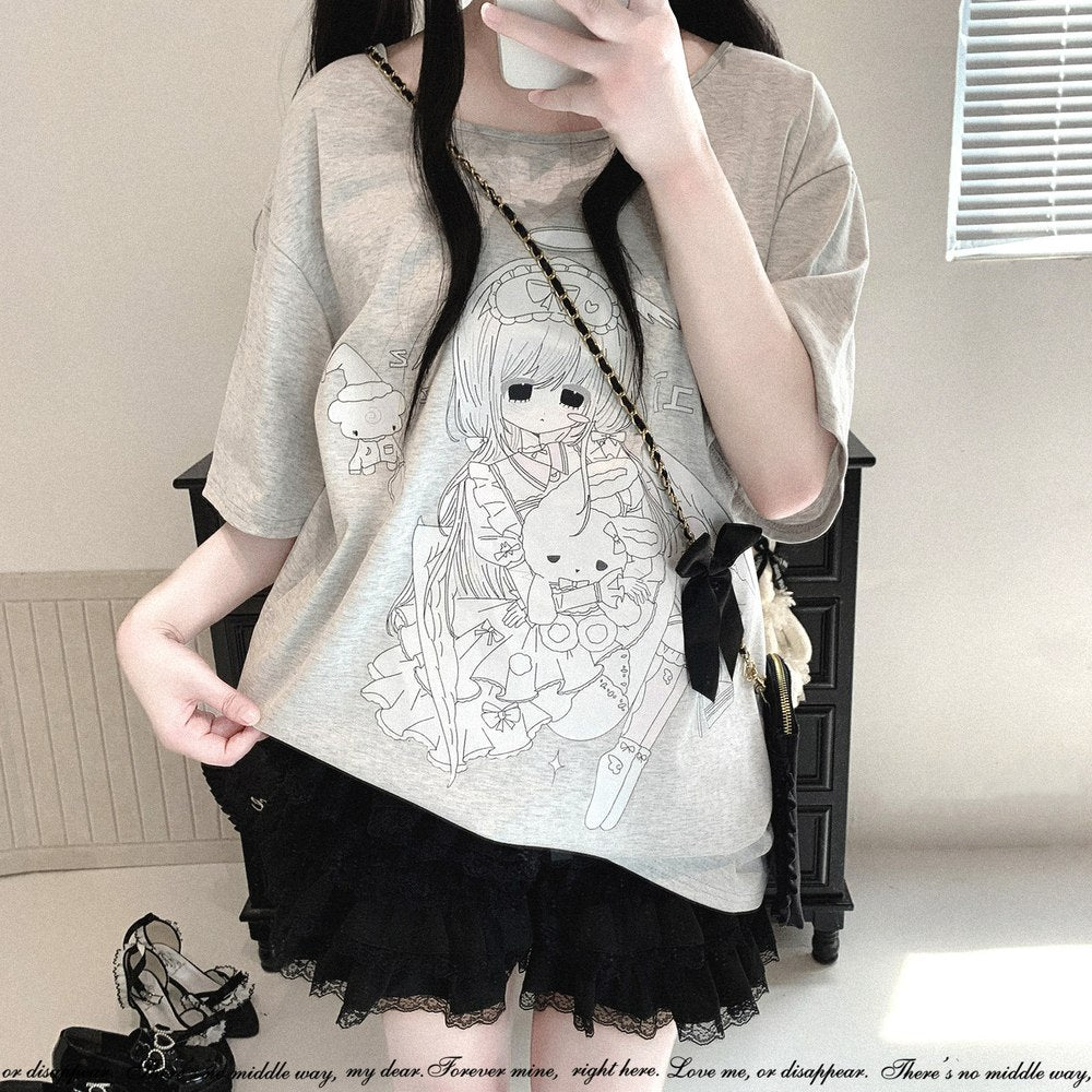 A person wearing an oversized light gray graphic T-shirt with a black-and-white anime-style character print, paired with a black ruffled skirt. The person is taking a mirror selfie indoors, holding a phone and wearing a small crossbody bag with a black bow and cream ribbon.