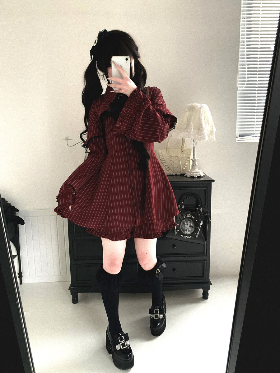 Person wearing a burgundy pleated dress with long sleeves in a room.