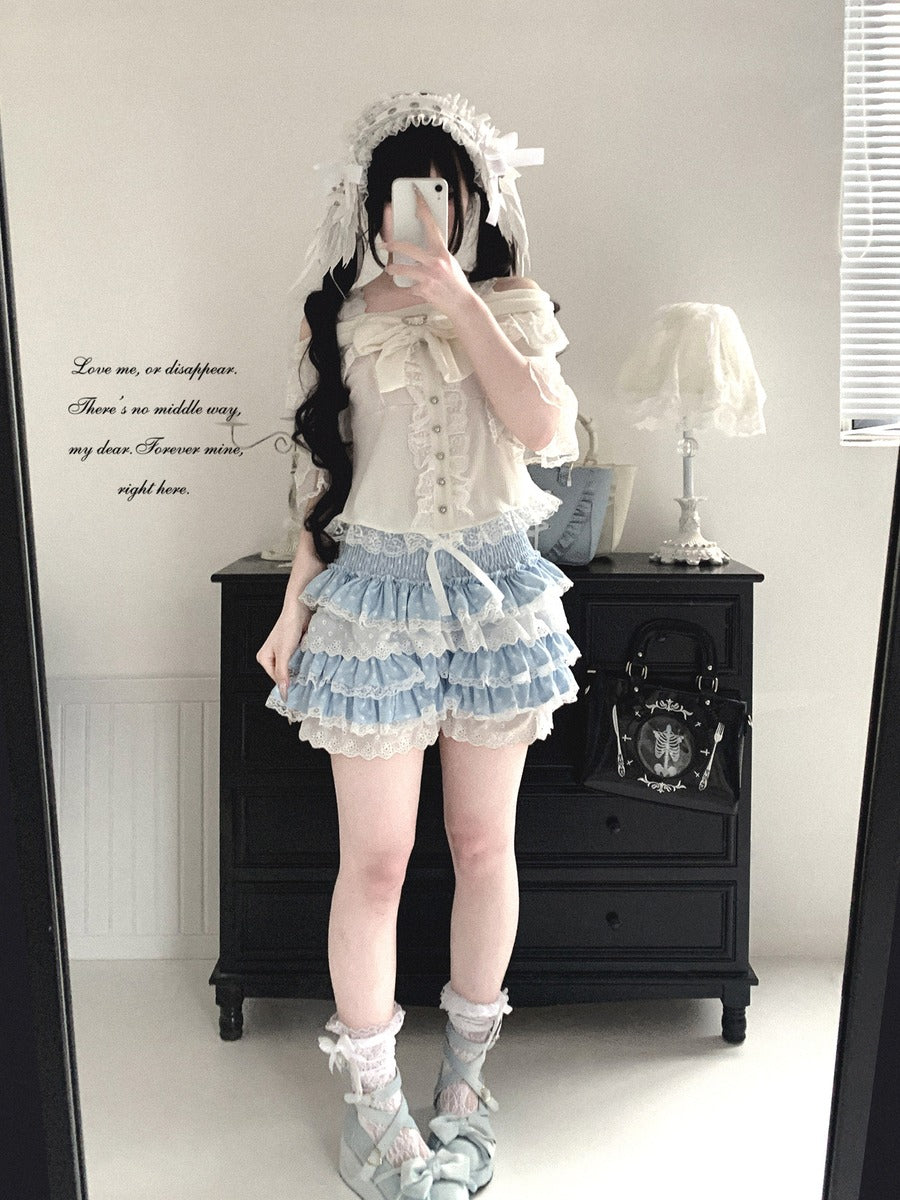 Person wearing a white and blue Lolita outfit in a room with a black dresser and white walls.