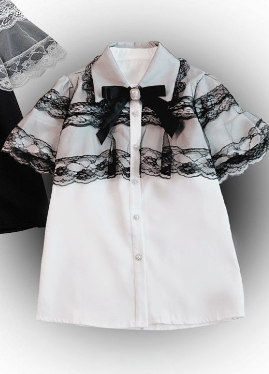 A white short-sleeve button-up shirt with black lace ruffle trim across the chest and sleeves, a black bow at the collar, and small silver buttons down the front.