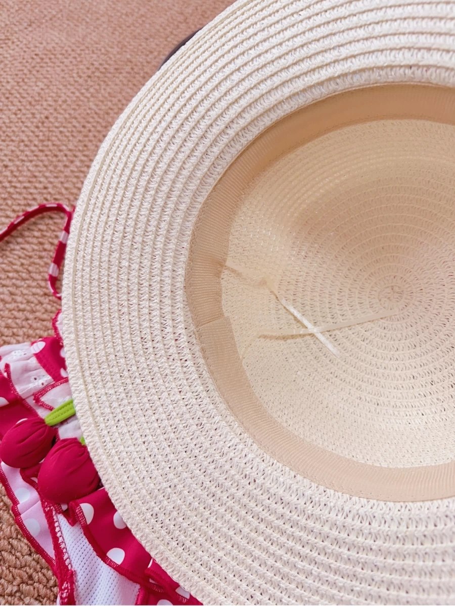 Close-up of a straw hat with a pink floral fabric underneath