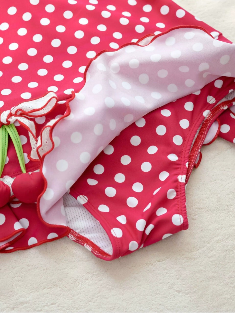 Red polka dot swimsuit with a bow on a light background