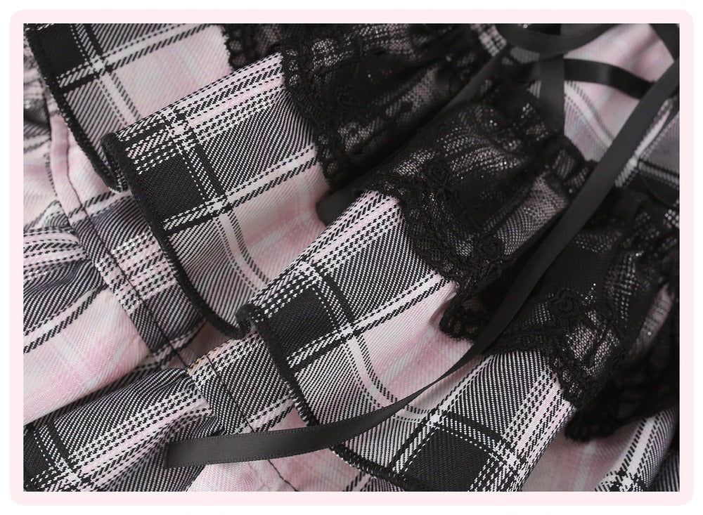 A close-up of a pink and black plaid fabric garment with black lace trim and black ribbon details.