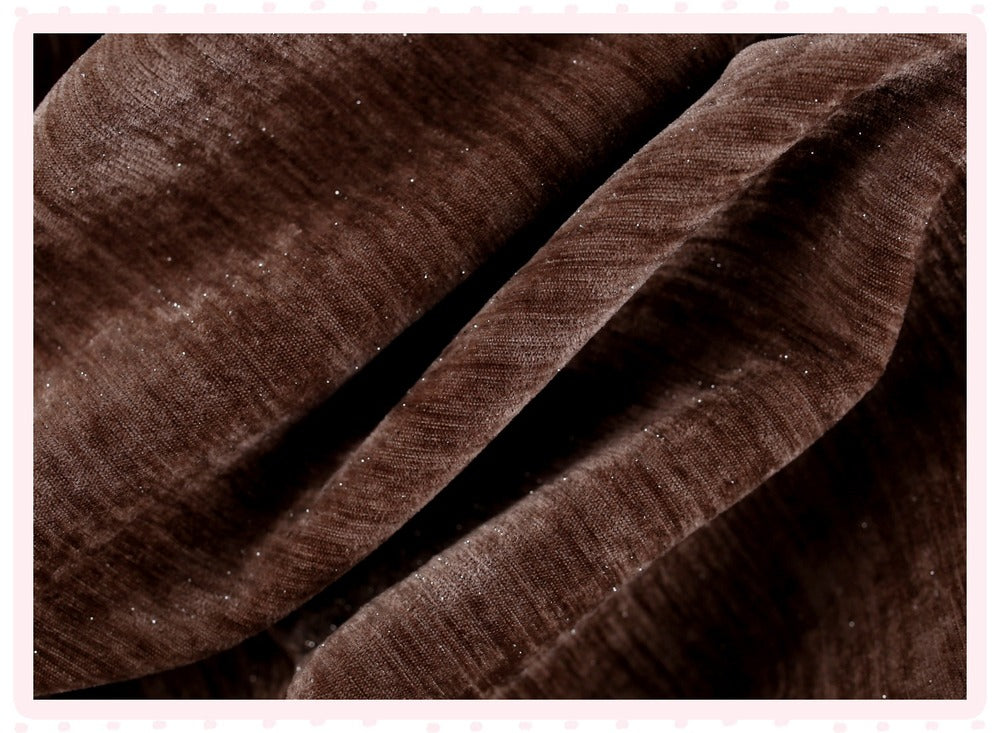A close-up of draped dark brown fabric with a subtle sheen and fine texture, framed by a light pink border.