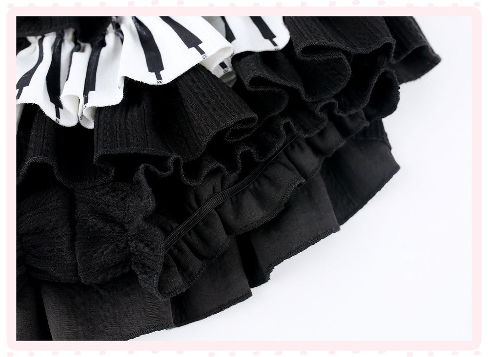 A close-up of a black ruffled skirt with a contrasting white and black striped ruffled trim, set against a white background with a light pink border.
