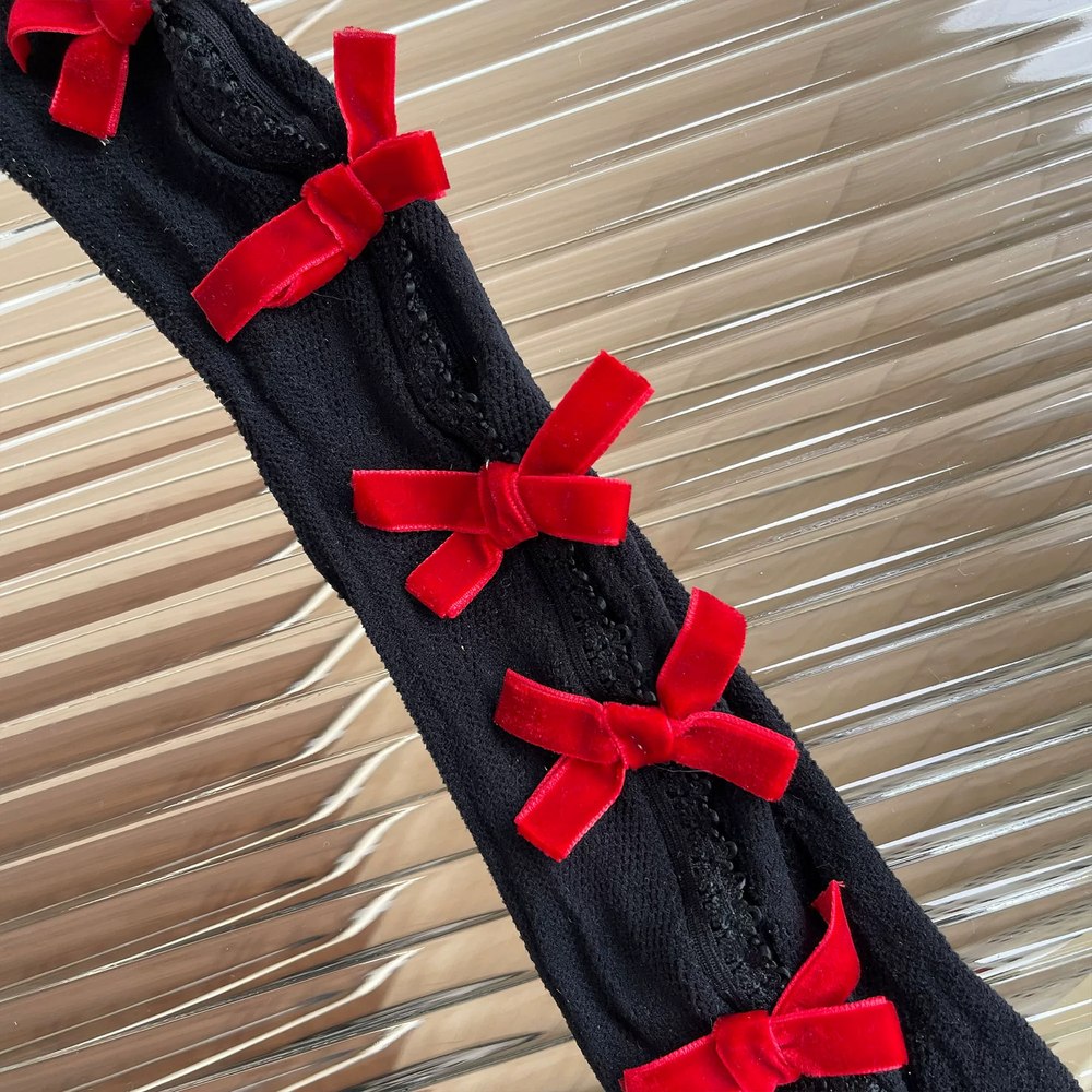 Black tights with red bows on a textured beige background