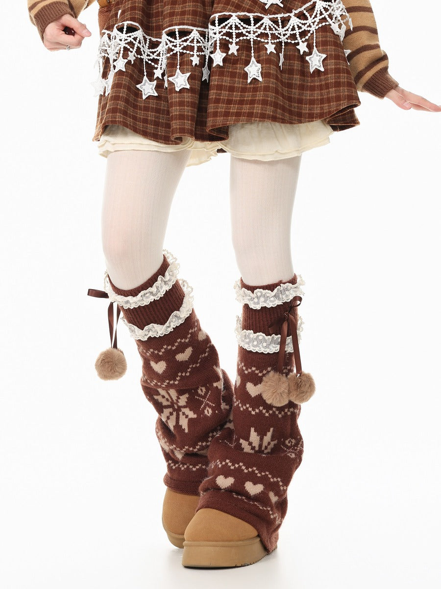 A person wearing brown knit leg warmers with cream lace trim, pom-poms, and a winter fair isle pattern, paired with brown platform shoes and a brown plaid skirt.