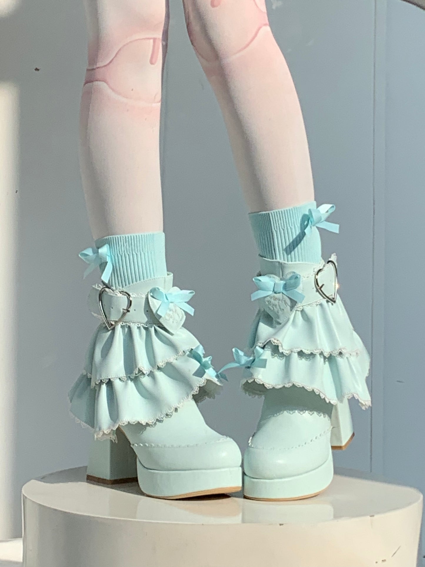 Light blue high-heeled shoes with ruffled details on a white background