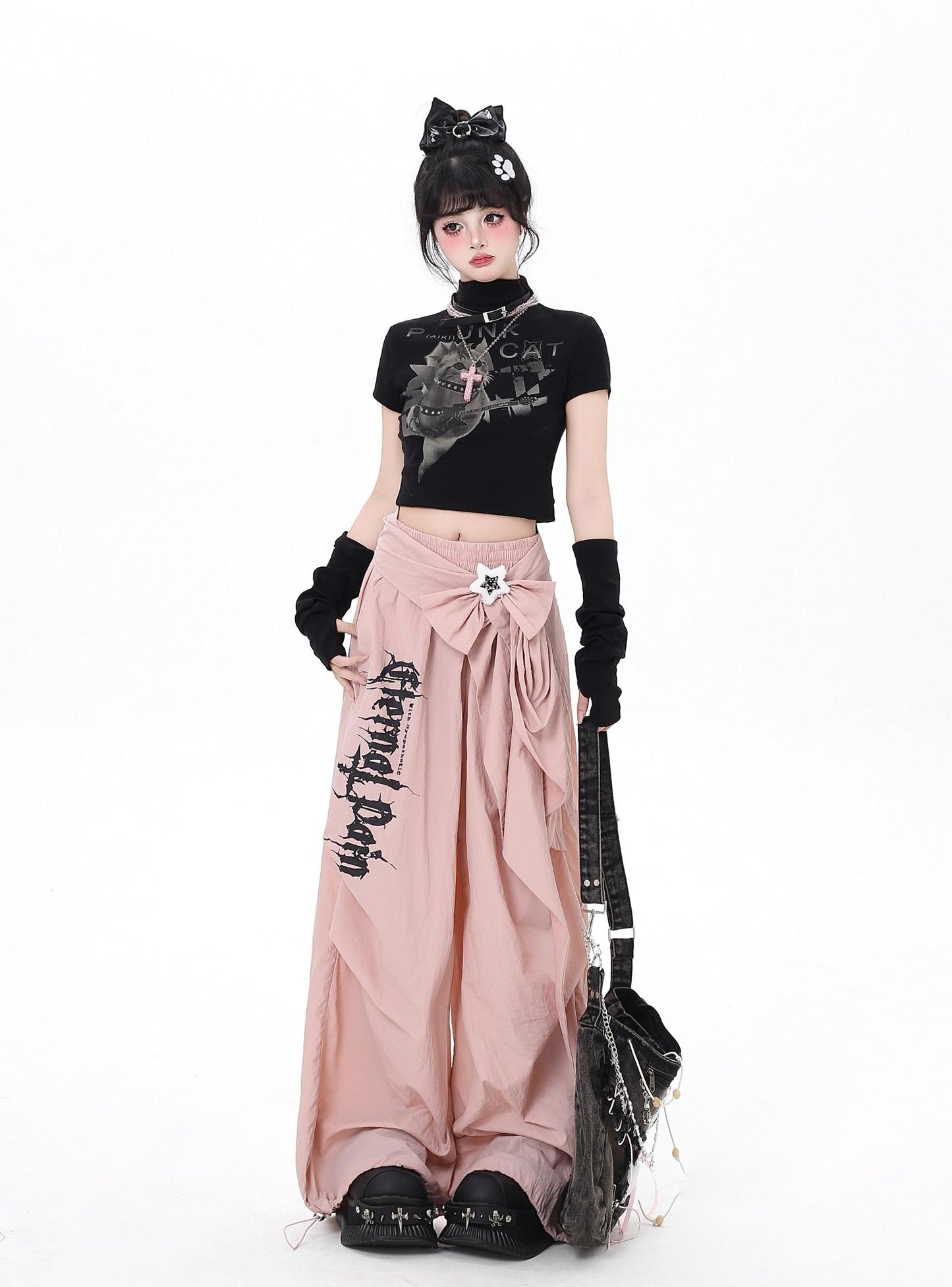 Person wearing a black top and pink skirt with text, standing against a white background