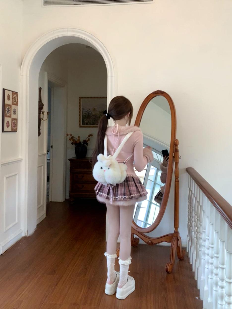 Person wearing pink coquette winter outfit standing in a home interior with a mirror and wooden floor.