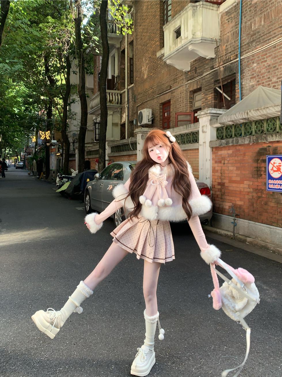 Person in a cute pink winter outfit with long hair and white shoes on a city street.