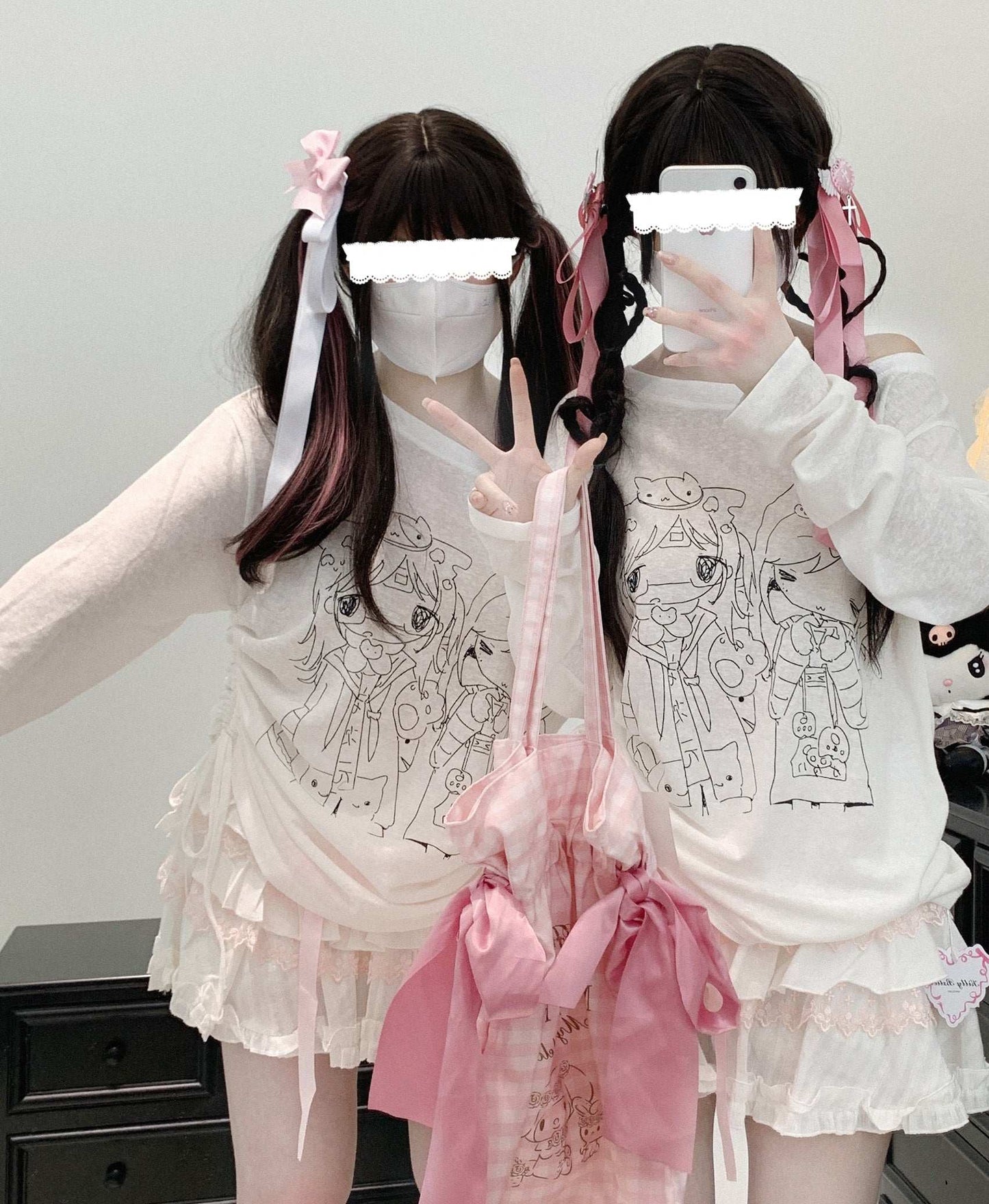 Two individuals wearing matching white off-shoulder sheer tops with flared sleeves and playful anime print.