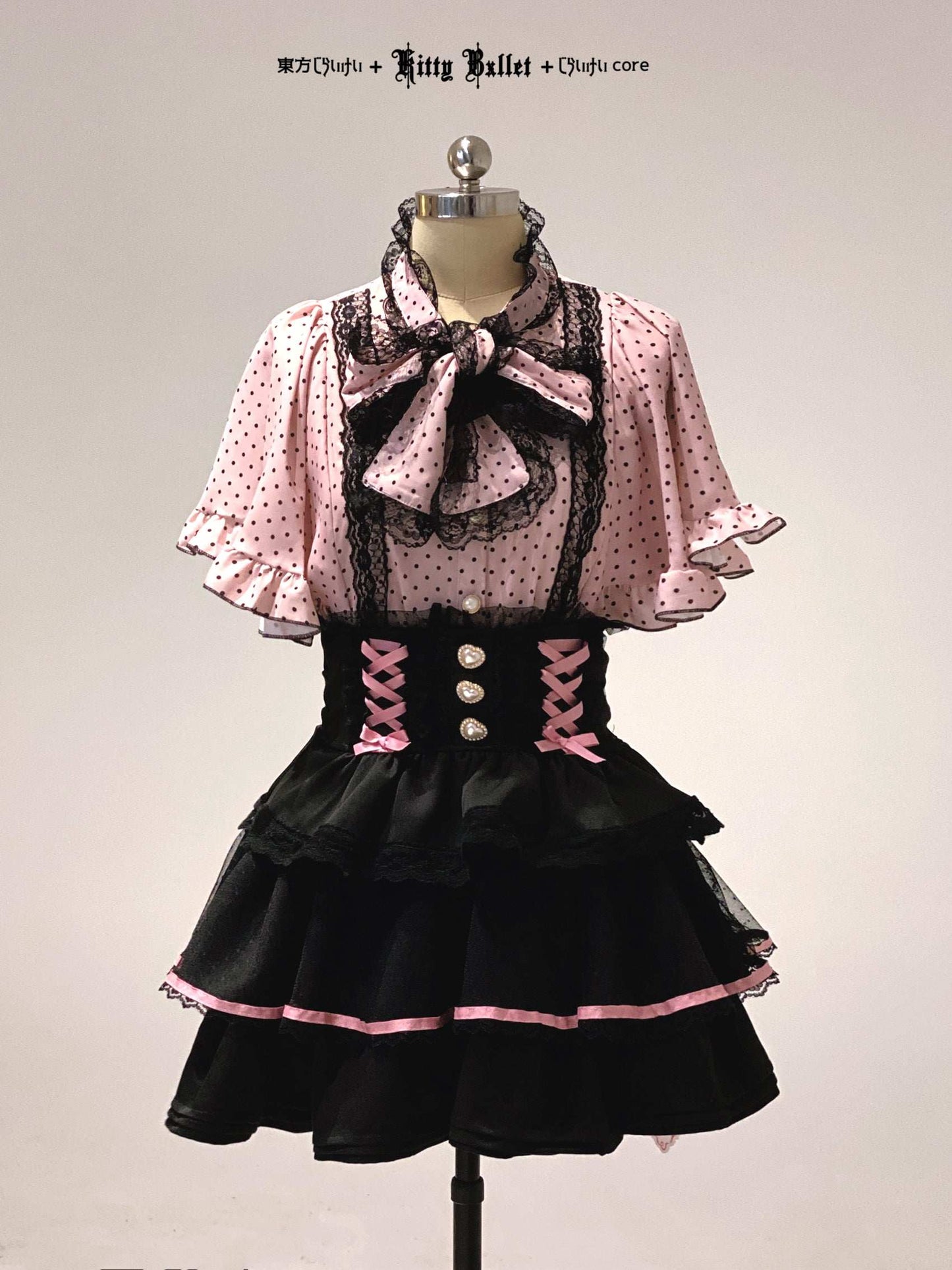 Black and pink jirai kei dress with a bow on a mannequin against a plain background