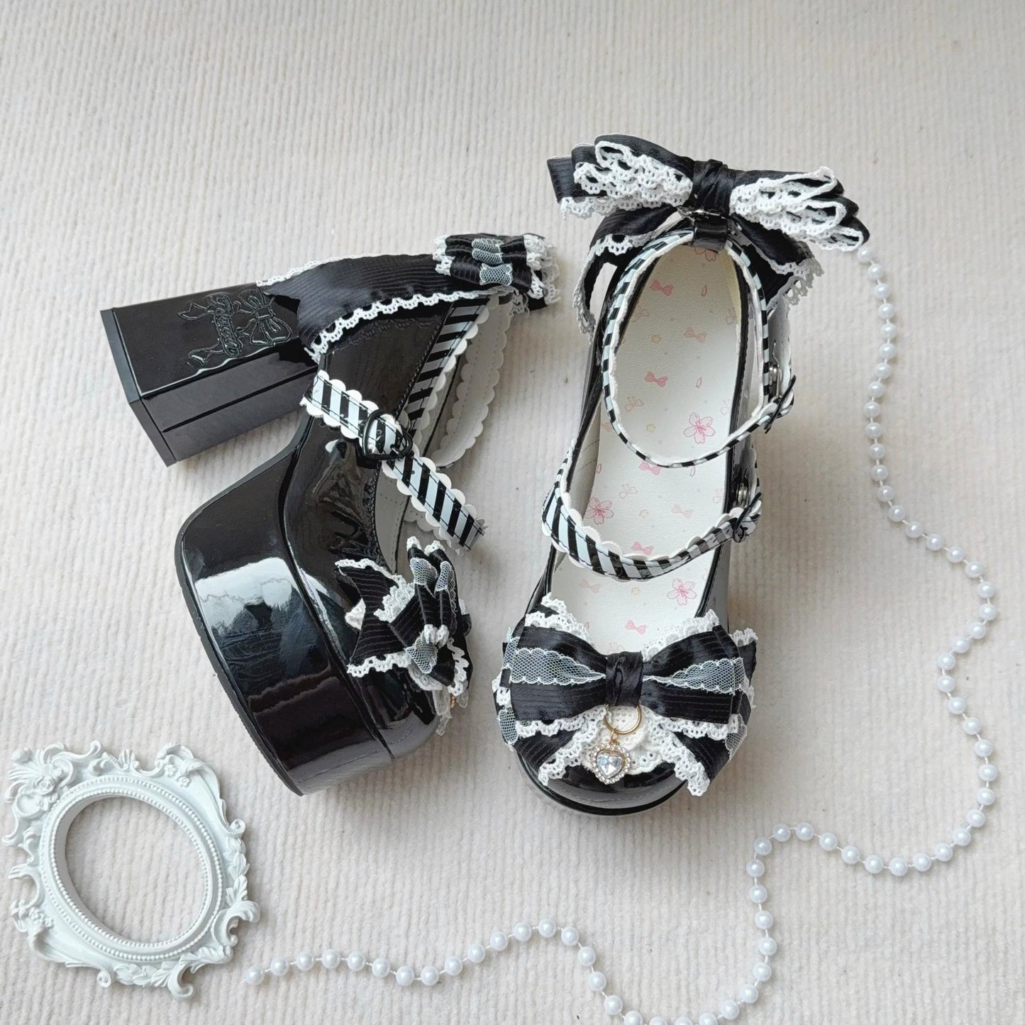 Black high-heeled shoes with decorative bows and ribbons on a light background
