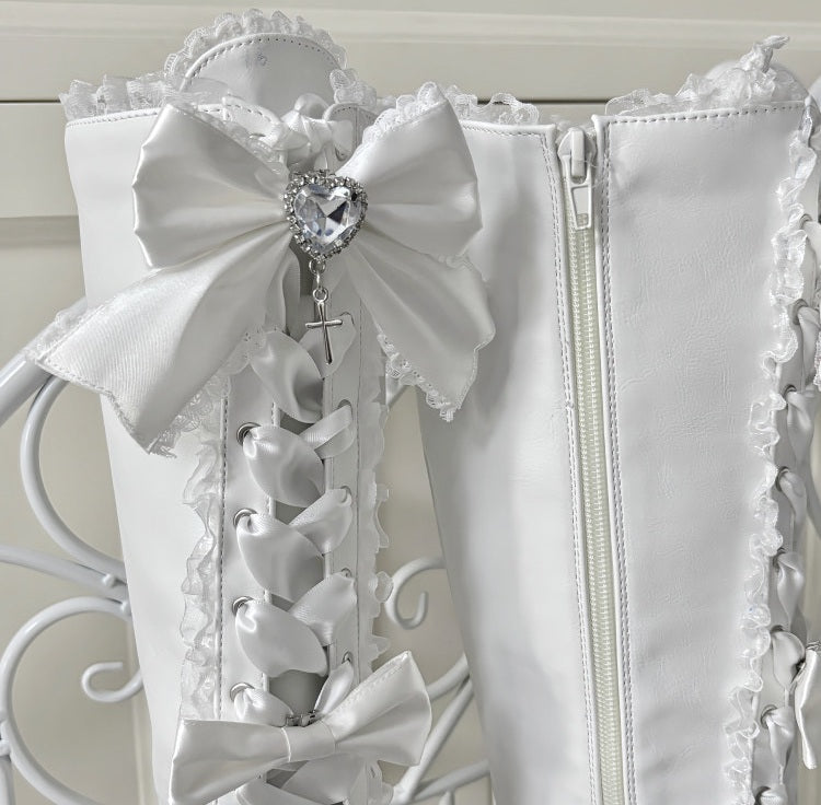 Close up of White boots with decorative bows and a zipper on a white background