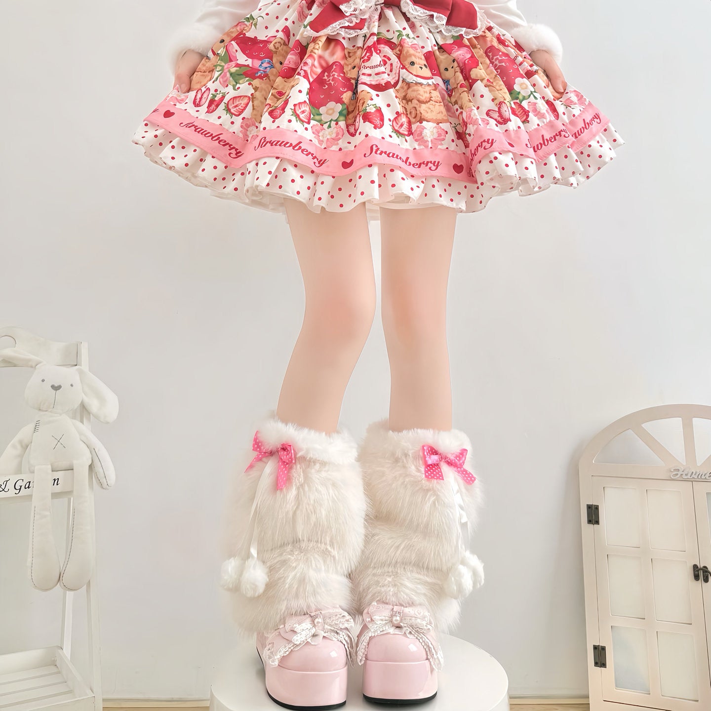 Person wearing a colorful dress with a strawberry pattern and white fluffy boots with pink bows.