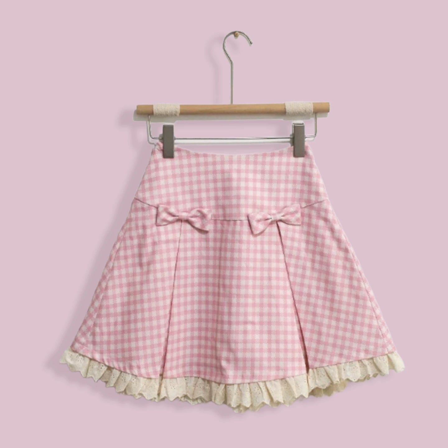 Pink gingham skirt with ruffle hem on a hanger against a pink background