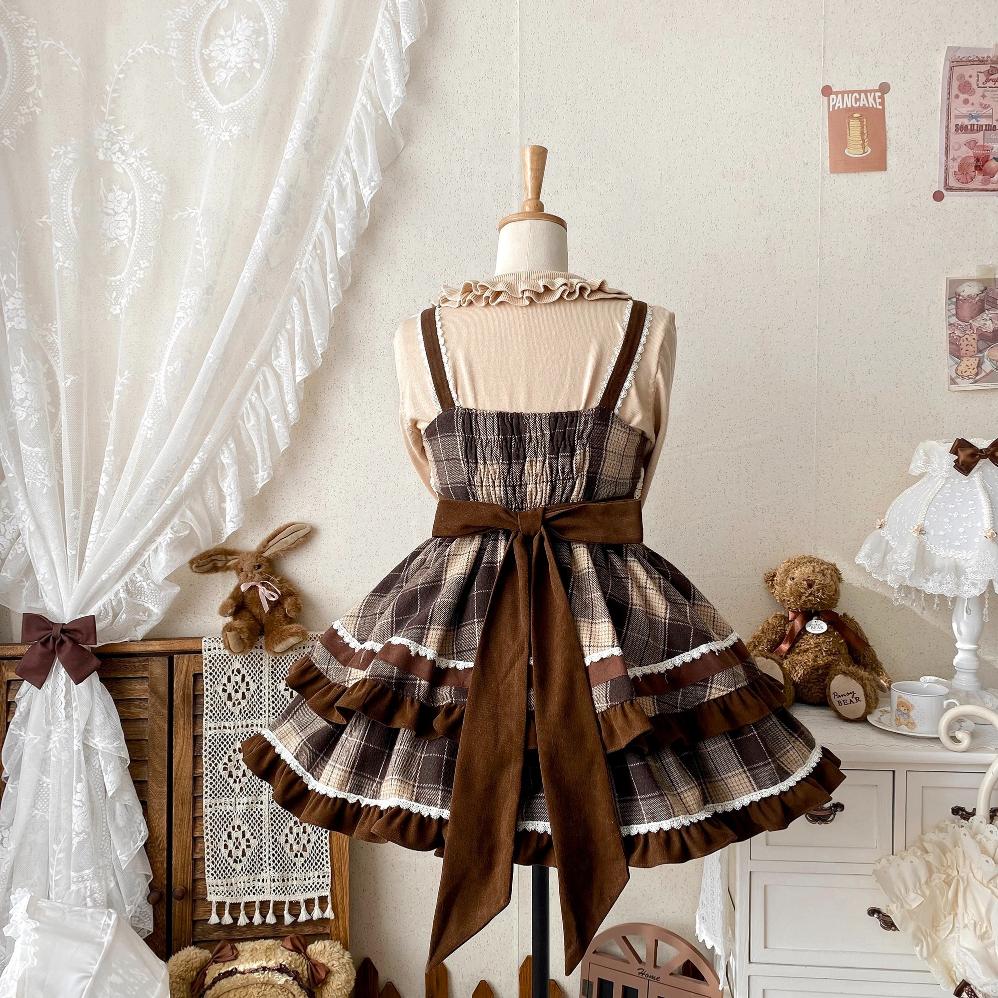 Plaid dress with a large brown bow on a mannequin against a decorative room background.