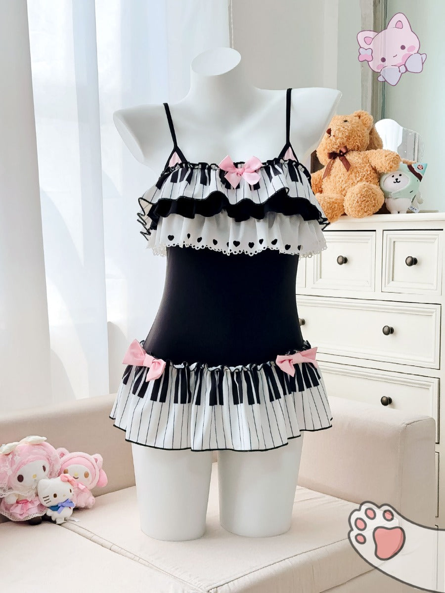 Black swimsuit with white ruffles on a mannequin, surrounded by teddy bears and a white cabinet.