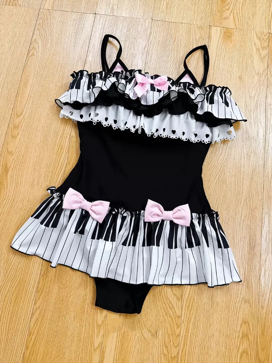 Black and white ruffled romper with pink bows on a wooden floor