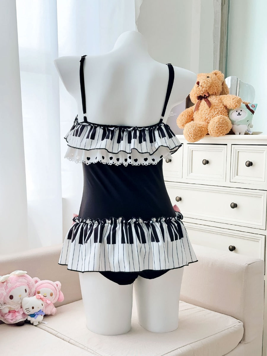 Mannequin wearing a black and white ruffled dress with piano key pattern, teddy bear and plush toys in the background.