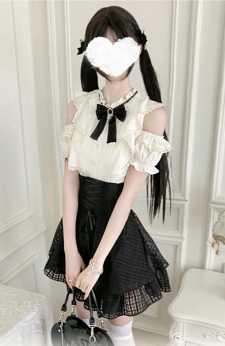 A person wearing a black and off-white Lolita-style outfit, featuring a cream-colored ruffled top with a large black bow at the collar, a black pleated skirt, white socks, and holding a black handbag. The face is obscured with a white heart-shaped censor block.