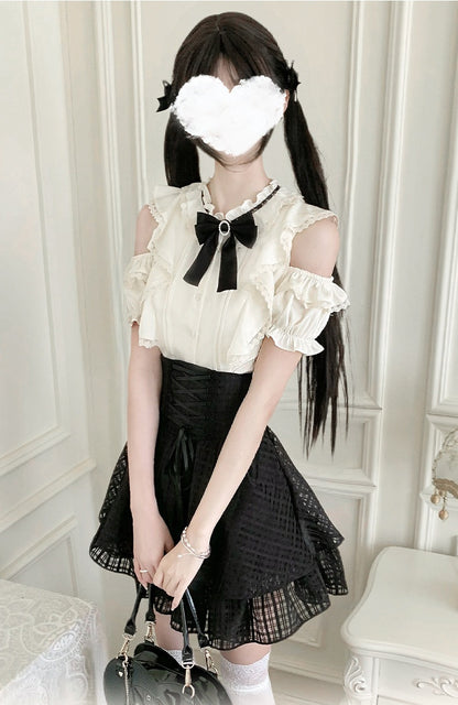 A person wearing a black and off-white Lolita-style outfit, featuring a cream-colored ruffled top with a large black bow at the collar, a black pleated skirt, white socks, and holding a black handbag. The face is obscured with a white heart-shaped censor block.