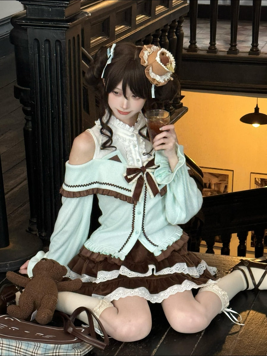 A woman wearing a detailed Lolita-style outfit with a mint green and brown dress, sitting on a wooden staircase. She is holding a glass of iced coffee and has a brown teddy bear on her lap.