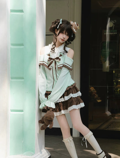 A young woman models a light mint green and brown lolita-style outfit with lace details, thigh-high socks, and a headband, posing next to a mint green door frame.