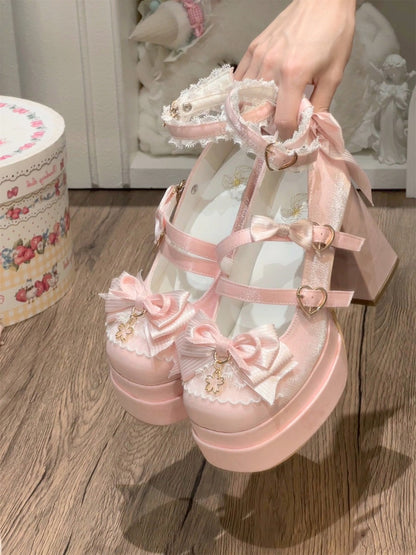 Pink lace-up shoes with bows held by a hand on a wooden floor.