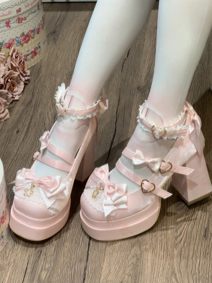 Pastel pink platform shoes with floral decorations on a wooden floor.