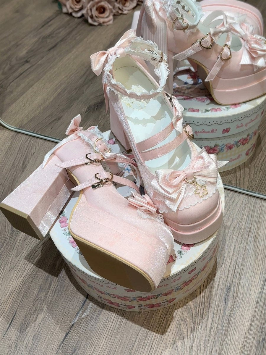 Pair of pink high-heeled shoes with decorative elements on a wooden surface.