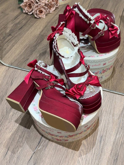 Red high-heeled shoes with decorative bows and flowers on a wooden surface.