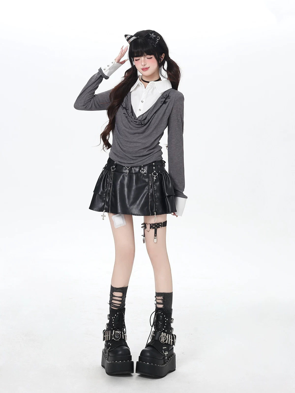 Person wearing a gothic outfit with a gray sweater, black leather skirt, and platform boots on a white background.