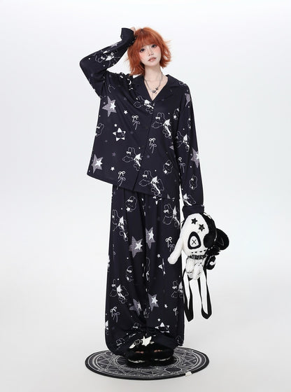 Person wearing a black cozy pajamas with white patterns, holding a white plush toy on a white background