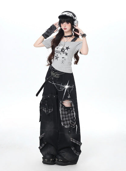 Person wearing a gray t-shirt with star designs and black ripped jeans on a white background