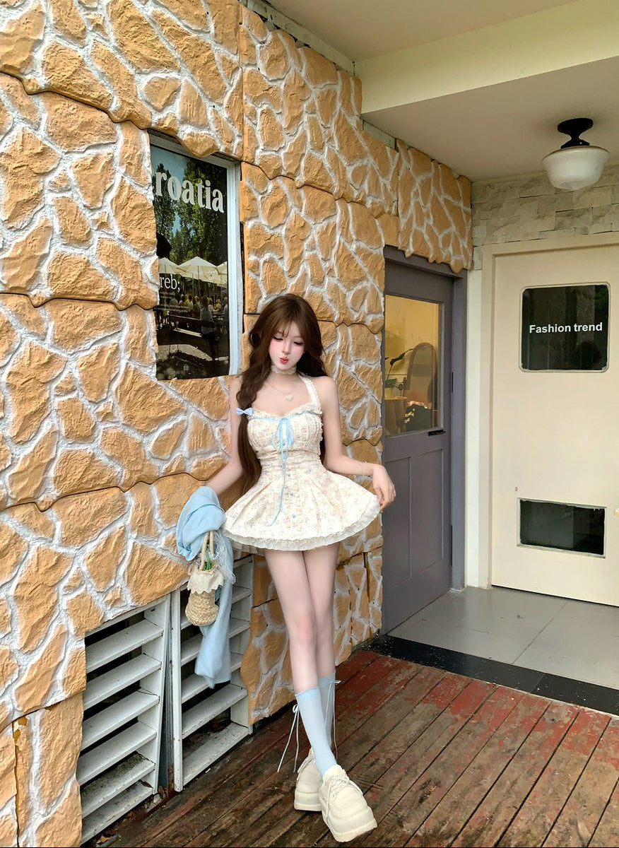 Woman in a white dress standing in front of a stone wall with a store entrance.