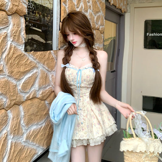 Woman in a lace dress standing against a stone wall with a store entrance.