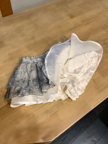 Two pairs of lace petticoats, one black and one white, on a wooden surface.