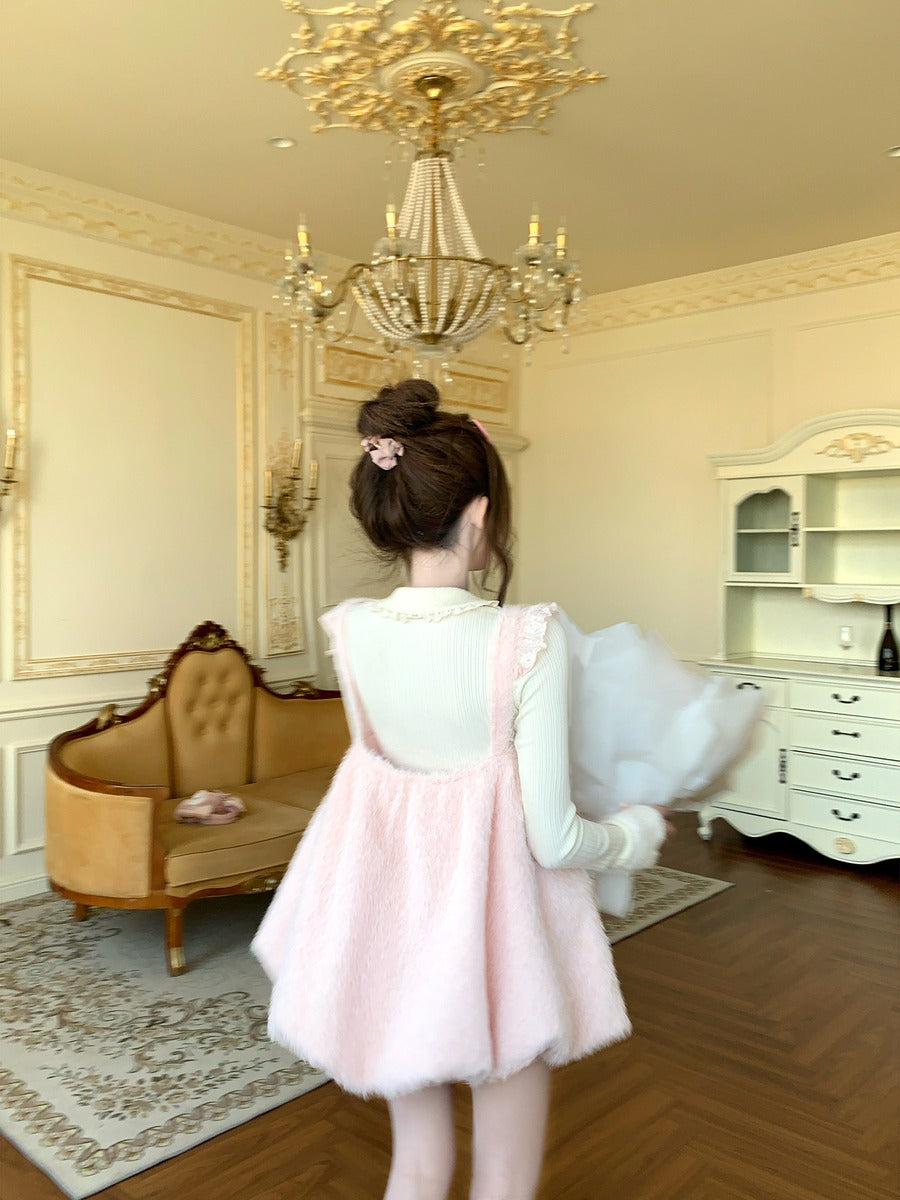 Person in a pink dress standing in an elegant room with a chandelier and furniture.