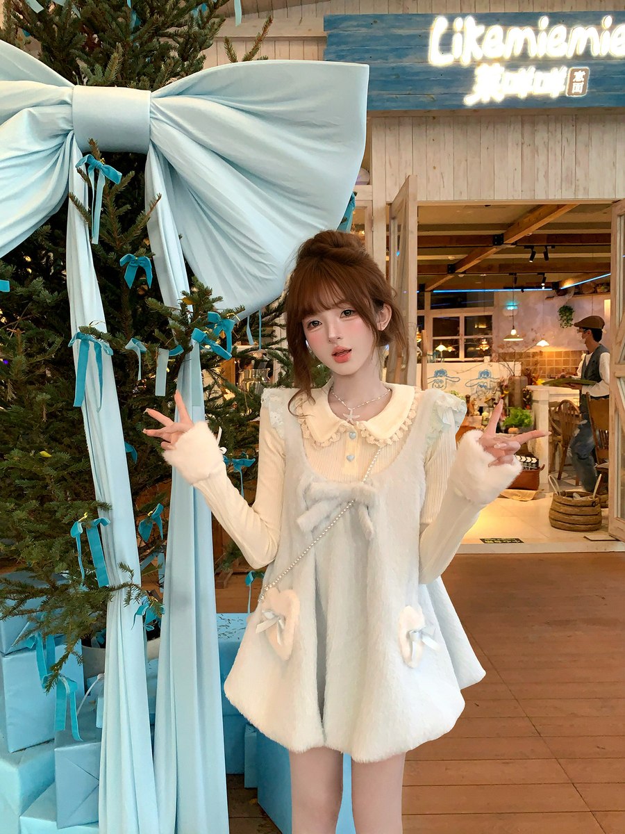 Woman in a white dress posing in front of a decorated Christmas tree and festive decor.