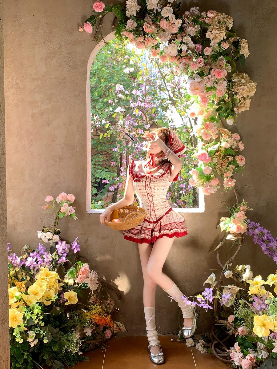 Person in a red dress standing in front of a floral archway with flowers on either side.