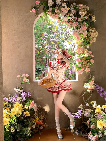Person in a red dress standing in front of a floral archway with flowers on either side.