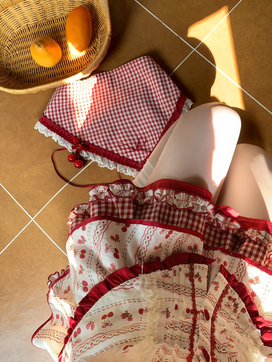 Person wearing a red and white checkered outfit with a basket of oranges on a tiled floor.
