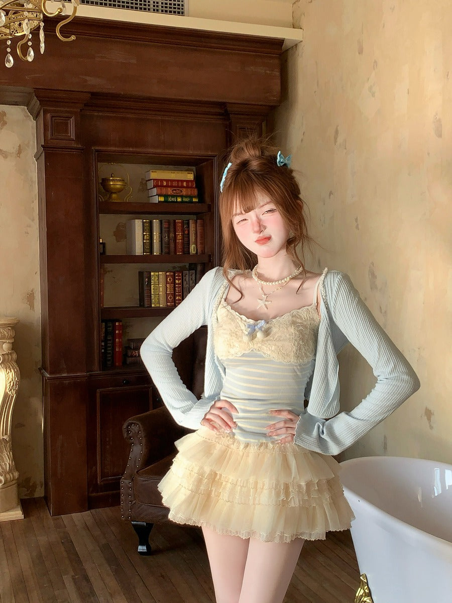 Woman in a light-colored dress with a gray cardigan standing in a room with wooden furniture and books.