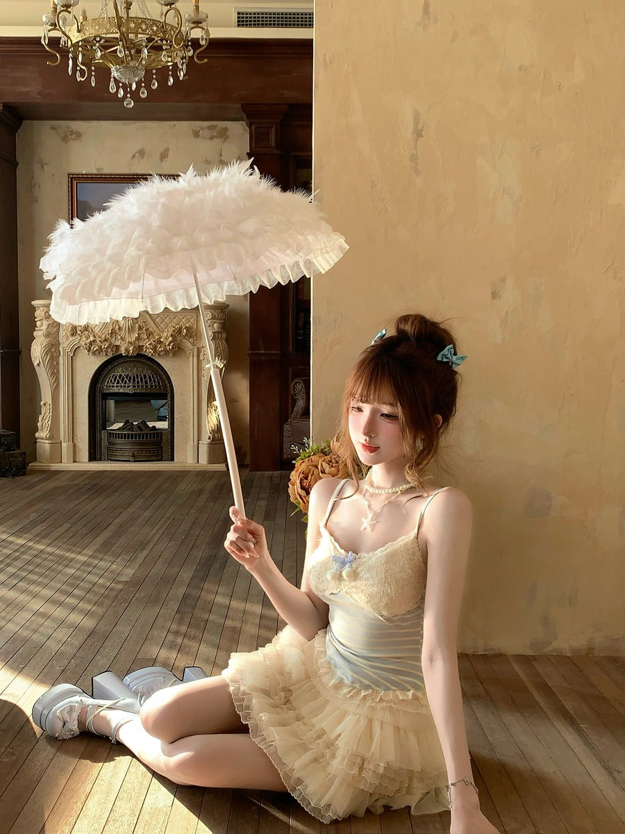 Woman in a vintage dress holding a large white feathered umbrella in an elegant room.