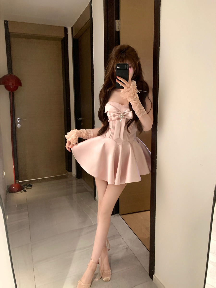 Person wearing a pink dress with lace sleeves in a room.